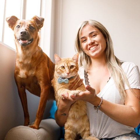 a woman sitting on a couch with a dog and a cat